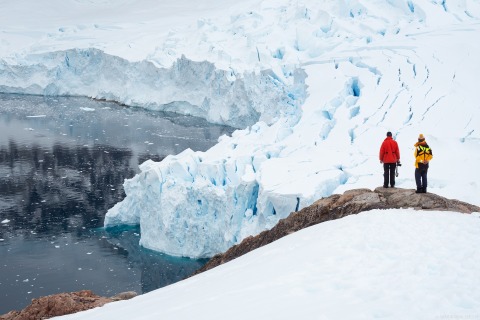 Zwei Besucher bestaunen die Gletscherfront bei Neko Harbour (Antarktische Halbinsel)